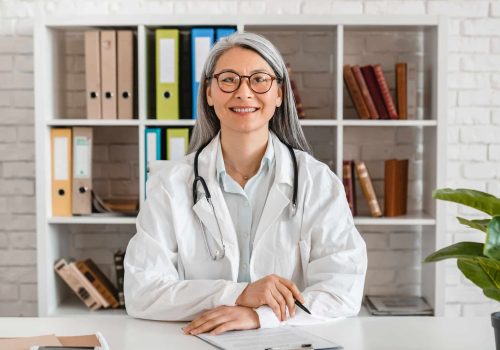 Happy middle-aged woman doctor sitting at the desk