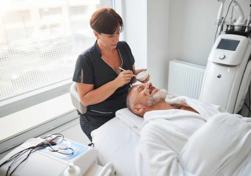 Spa therapist preparing a lotion for an aging man