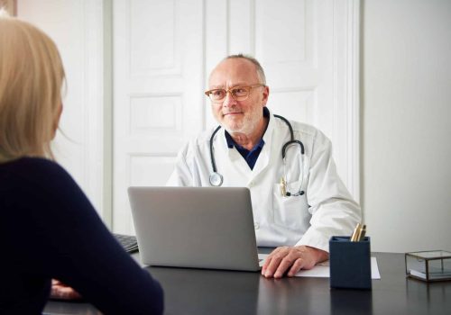 Therapist listening to patient at laptop in hospital